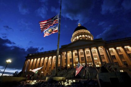 Charlie Kirk supporters Thomas Hess and Nolan Jenson stand in front of the Utah Capitol with flags to honor him,, Sept. 10, 2025.
