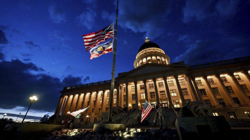 Charlie Kirk supporters Thomas Hess and Nolan Jenson stand in front of the Utah Capitol with flags to honor him,, Sept. 10, 2025.